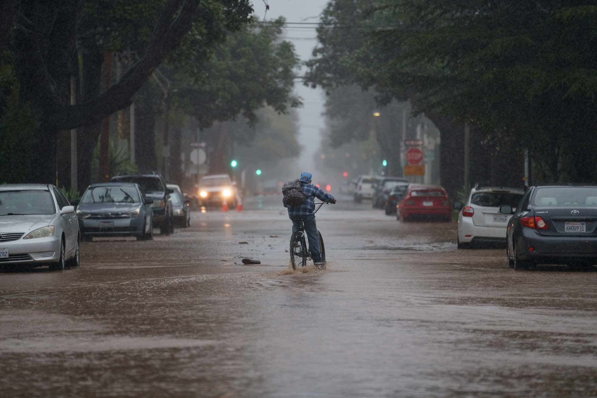 Một người đạp xe qua vùng nước lũ trong cơn mưa ở Santa Barbara, California, vào ngày 4/2 - Ảnh: Eric Thayer/Bloomberg/Getty Images