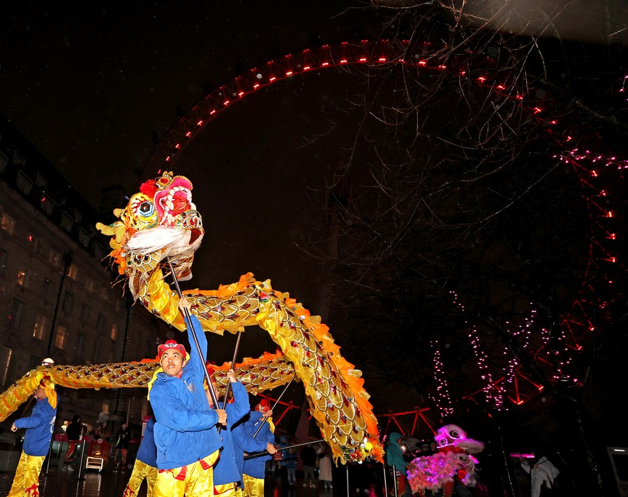 Các nghệ nhân múa rồng truyền thống của Trung Quốc biểu diễn trước vòng quay London Eye được thắp sáng màu đỏ để chào mừng Tết Nguyên đán ở London, Anh - Ảnh: Tân Hoa Xã/Li Ying