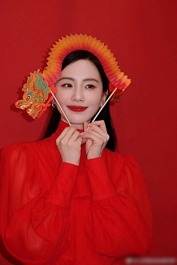 Lưu Thi Thi mặc váy đỏ, cổ cao kín đáo và trang điểm nhẹ nhàng, cách tạo dáng dễ thương giúp bà xã Ngô Kỳ Long hack tuổi hiệu quả.