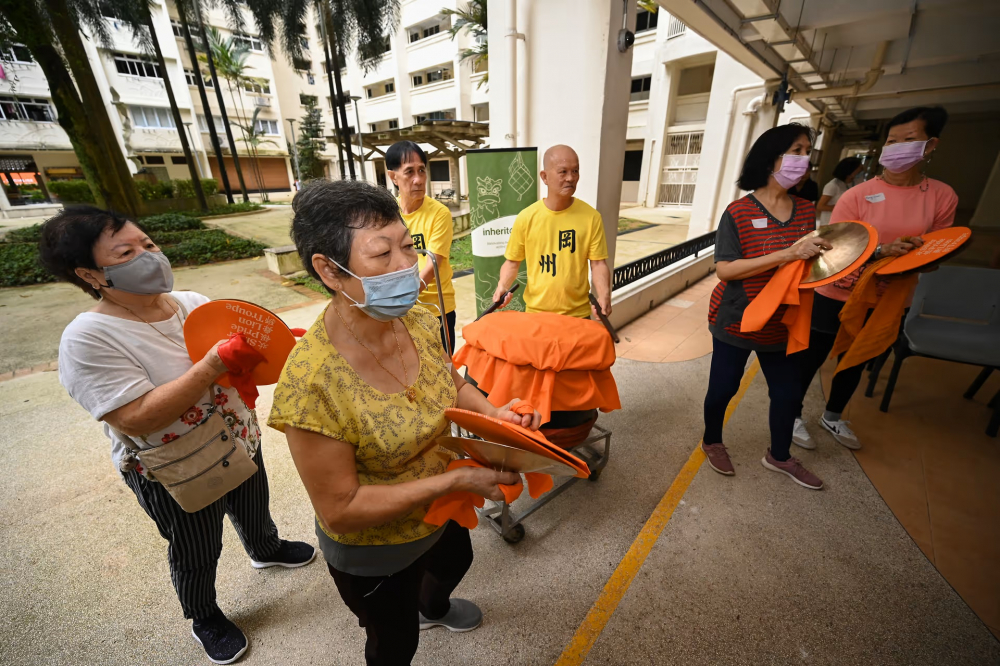 Bà Chew Ai Choo (80 tuổi), bà Teo Poh Eng (73 tuổi), bà Chua Ai Geok (71 tuổi) và bà Nancy Choo (68 tuổi) chơi chũm chọe cùng hai thành viên của hiệp hội Kong Chow Wui Koon (áo vàng)