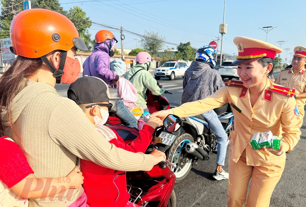 Thượng úy Nguyễn Lê Mỹ Nhân - cán bộ Phòng CSGT Công an tỉnh Vĩnh Long cùng lực lượng “đội nắng” phát nước suối và sữa miễn phí cho dân