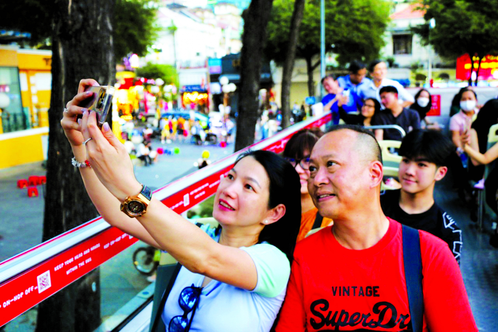 Du khách chụp hình lưu niệm trên xe buýt hai tầng ở TPHCM ngày mùng Ba tháng Giêng - Ảnh: Quốc Thái