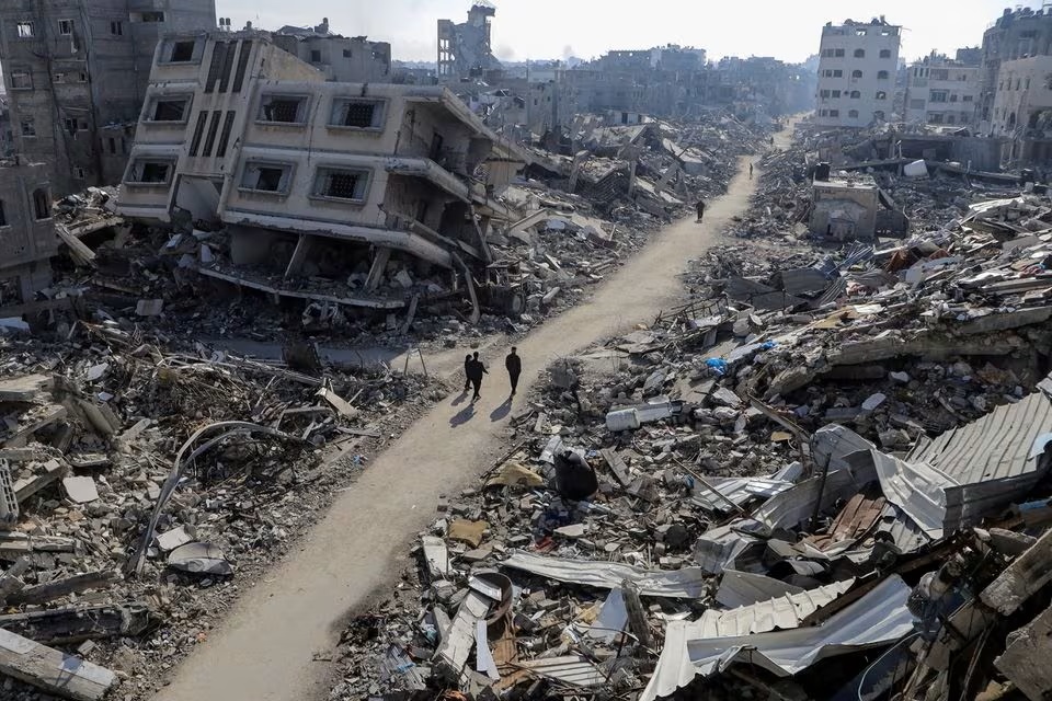 Người Palestine đi ngang qua những ngôi nhà bị phá hủy trong bối cảnh xung đột đang diễn ra giữa Israel và Hamas, tại trại tị nạn Jabalia, phía bắc Dải Gaza ngày 22/2/2024 - Ảnh: REUTERS/Mahmoud Issa