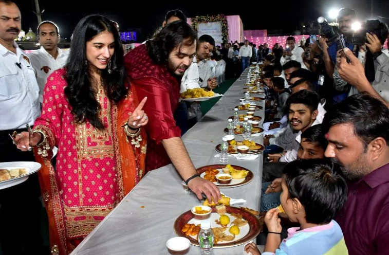 Ông Anant Ambani, con trai của Mukesh Ambani, và bà Radhika Merchant, đang phục vụ món ăn Gujarati truyền thống cho dân làng trước lễ kỷ niệm trước đám cưới của họ. ẢNH: REUTERS