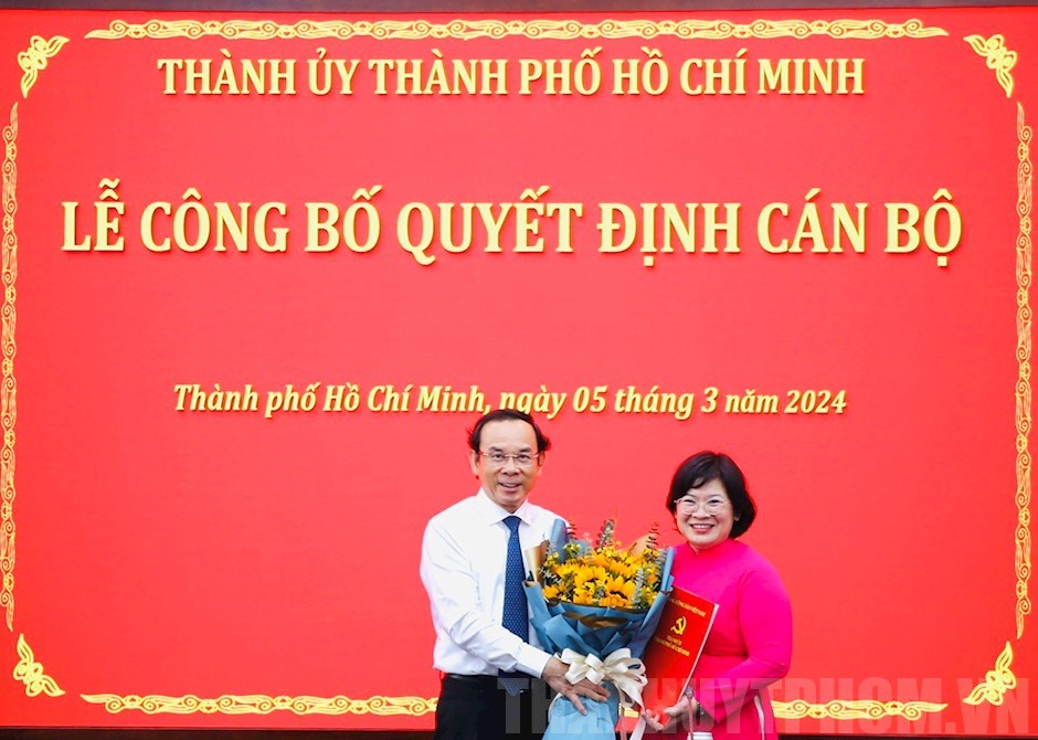 Nguyễn Văn Nên trao quyết định và hoa chúc mừng bà Văn Thị Bạch Tuyết - Ảnh:Long Hồ 