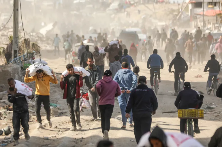 Người Palestine chạy đến những chuyến xe viện trợ nhân đạo ở thành phố Gaza - Ảnh: AFP
