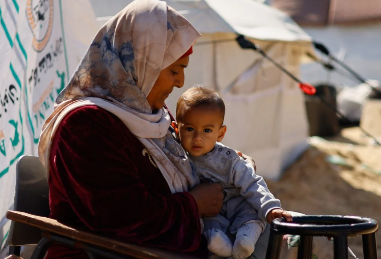 Một người phụ nữ bế em bé khi những người Palestine di tản chạy trốn khỏi nhà do các cuộc tấn công của Israel đến nơi trú ẩn ở Rafah ở phía nam Dải Gaza vào tháng 2. Ảnh: Reuters