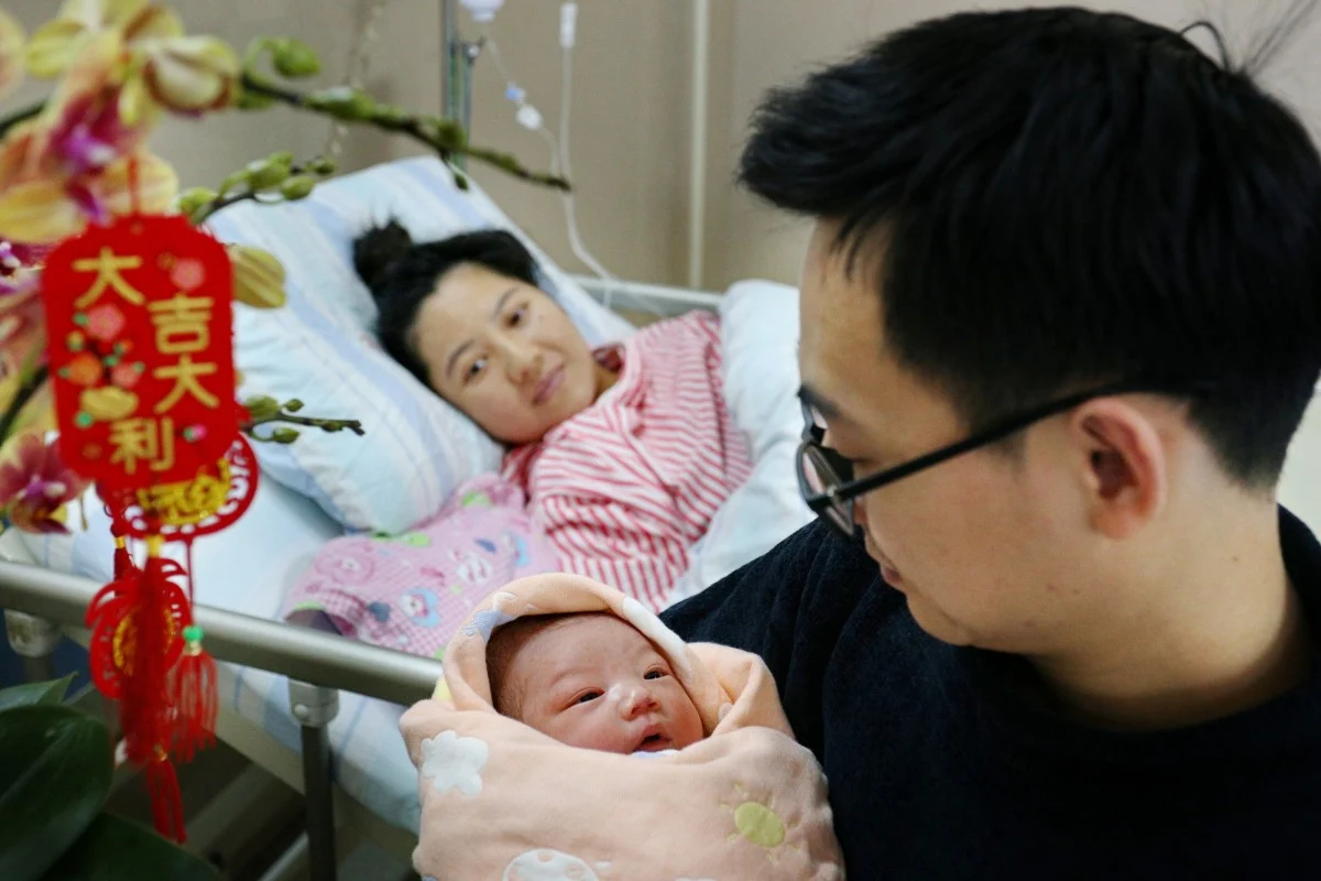 Một cặp vợ chồng Trung Quốc chụp ảnh cùng đứa con mới sinh tại một bệnh viện tỉnh Quảng Đông vào ngày 10/2, ngày đầu tiên của Năm con Rồng - Ảnh: Tân Hoa Xã