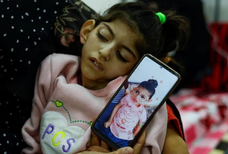 Người mẹ Umm Mesbah Heji đang ôm cô con gái suy dinh dưỡng Israa, bị liệt tứ chi và động kinh. ẢNH: REUTERS