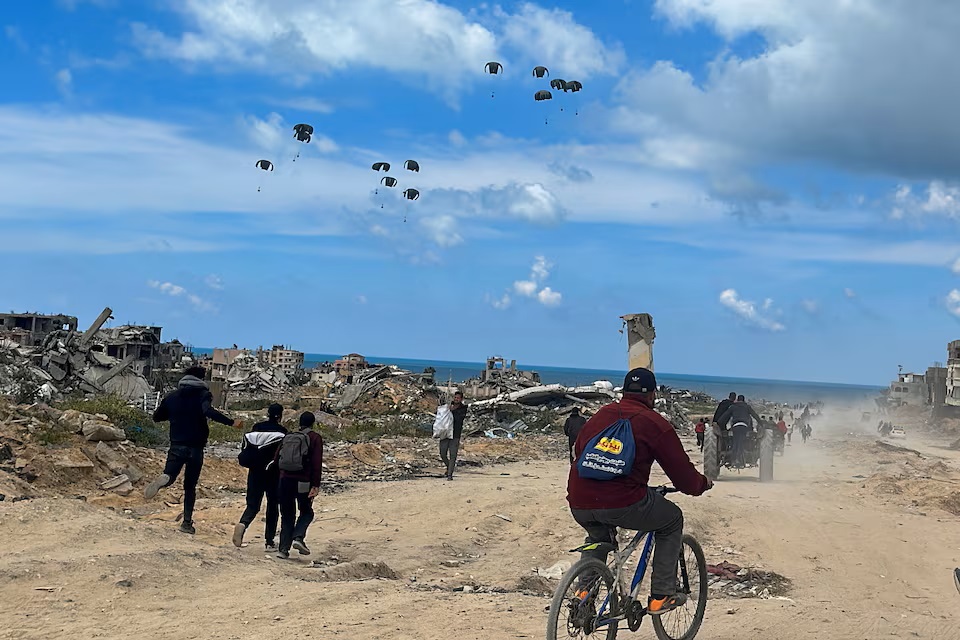 Người Palestine đổ xô ra bãi biển để nhận hàng viện trợ do máy bay thả xuống hôm 25/3 - Ảnh: Reuters