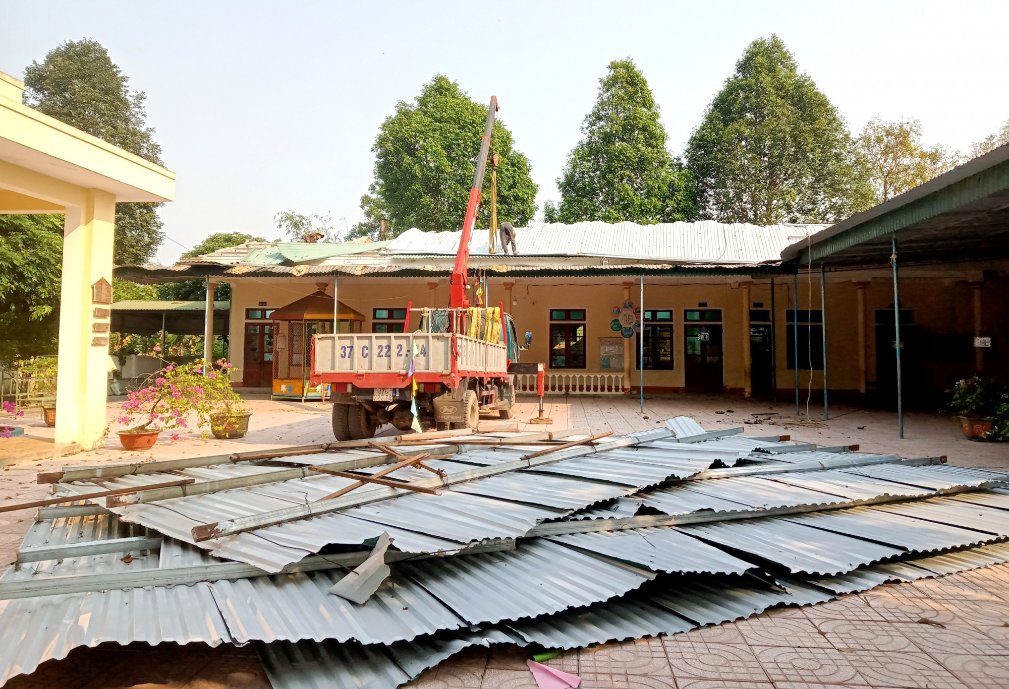 Trường Mầm non xã Sơn Hồng thuê thợ tháo dỡ mái tôn treo lơ lửng để sớm đón học sinh trở lại lớp - Ảnh: Trần Sự