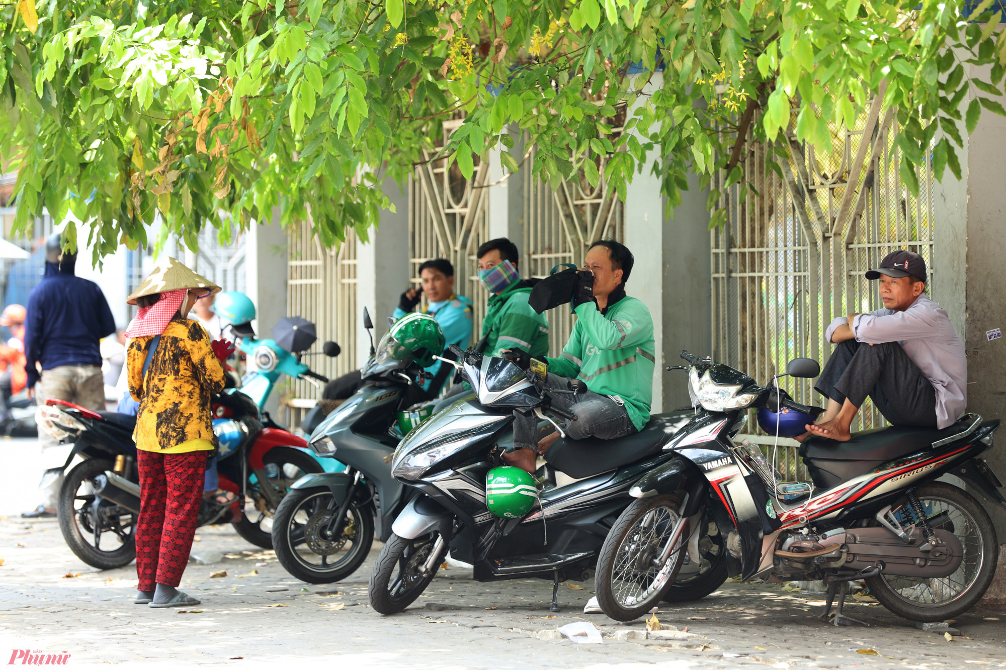 Bóng mát của những tán cây là nơi tránh nắng của người lao động thường xuyên ở ngoài trời như xe ôm, shipper, người bán vé số,