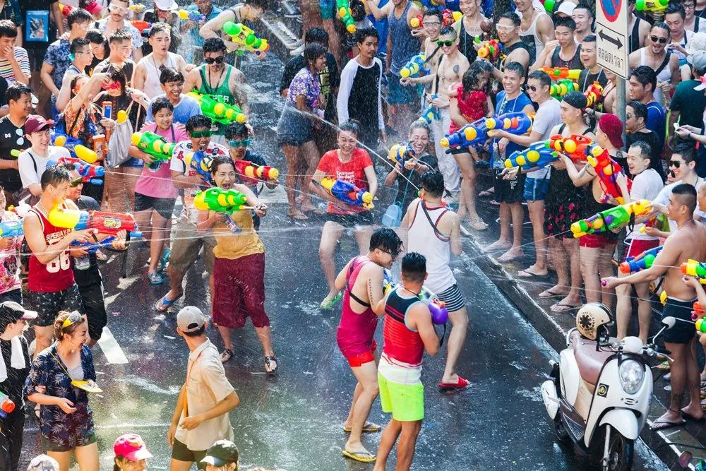 Các địa điểm hút du khách dịp Songkran: Silom khi thường nhật là một khu vực hành chính tấp nập với các tòa nhà cao tầng to lớn, văn phòng cao ốc trải dài và người dân thì bận rộn. Tuy vậy khi về đêm Silom lại khoác lên mình một bộ dạng rất khác với các nhà hàng, quán bar, chợ đêm cực kỳ sôi động. Silom có vẻ rất giống với Sài Gòn của ta vậy. Vào những ngày Tết Songkran diễn ra, Silom trở thành nơi mà “cuộc chiến” té nước diễn ra quyết liệt nhất.    Mọi người ùa ra đường với súng nước và xô chậu, tràn lên khắp đường phố, thậm chí là cả những con đường đi bộ trên cao. Cuộc chiến có thể diễn ra từ sáng tới tối và dọc con phố có rất nhiều cửa hàng để bạn mua “vũ khí” nước cho riêng mình. Sau 7h tối không khí thậm chí còn đông đúc đến mức bạn không thể đi dạo phố luôn đó!  Silom thuộc trung tâm nên có thể dễ dàng di chuyển đến nhiều khu vực khác. Tuy vậy bạn không nên chọn đi taxi vì đường phố cũng hay diễn ra tình trạng kẹt xe. Lựa chọn các hệ thống tàu điện trên cao (BTS) hoặc giao thông đại chúng tốc độ cao (MRT) sẽ thuận tiện hơn rất nhiều.