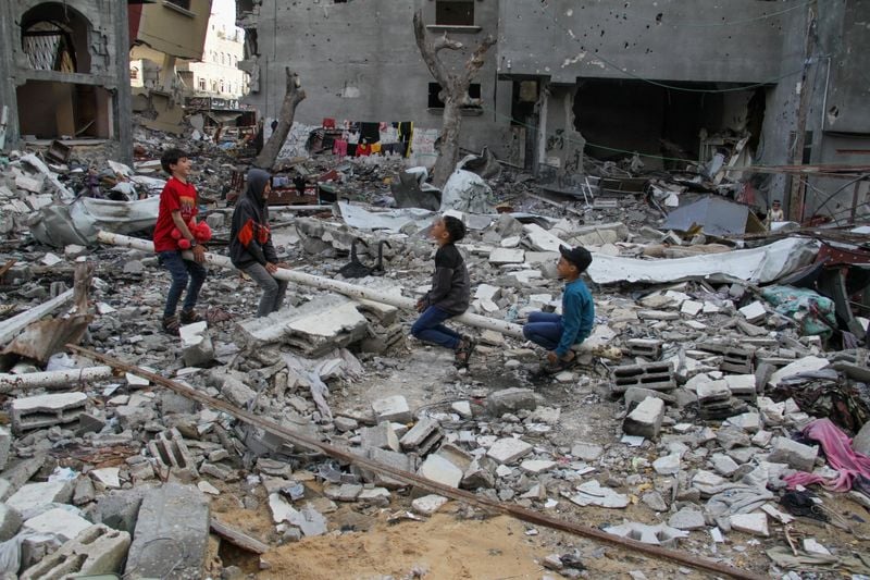 Các em ngồi giữa đống đổ nát chơi bập bênh ở Gaza - Nguồn ảnh: Reuters.