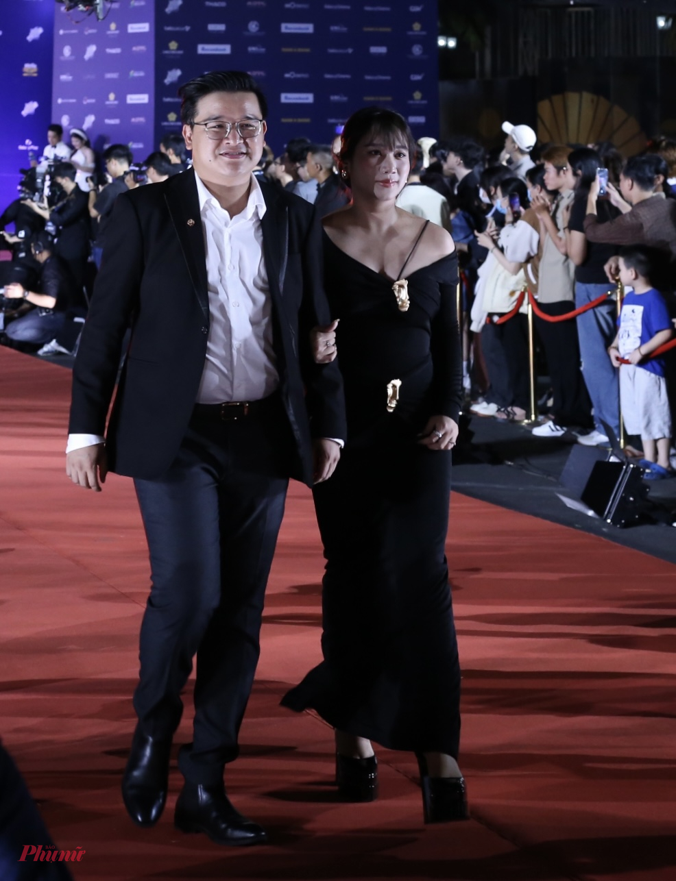Đạo diễn Võ Thanh Hoà cùng vợ - nhà sản xuất Mai Bảo Ngọc dự đêm bế mạc sự kiện. Trên nhiều thảm đỏ, cặp vợ chồng cũng thường mặc trang phục đen, tiết chế phụ kiện.