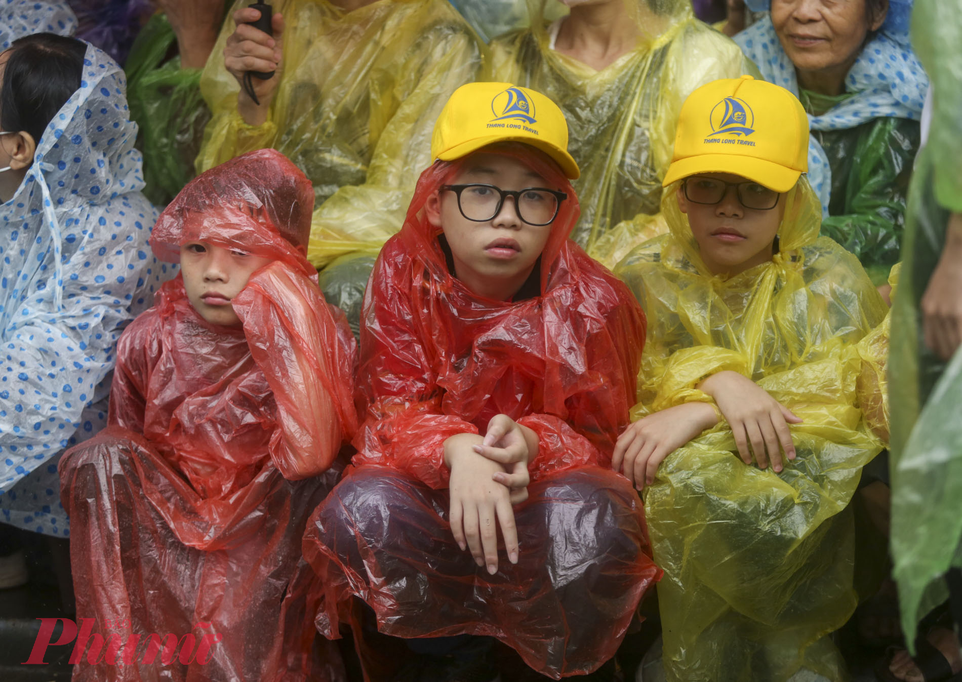 Những đứa trẻ tỏ ra mệt mỏi khi phải chờ đợi dưới cơn mưa lớn.
