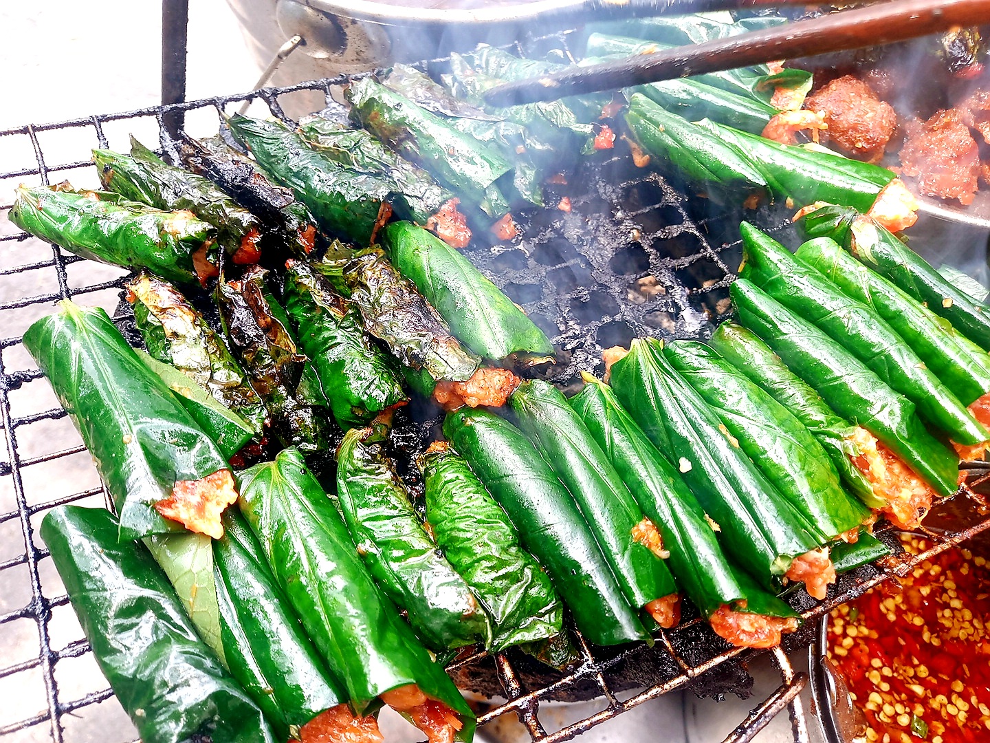 Bò nướng bọc lá trầu (Bò lá lốt) (Thịt Bò Nướng Lá Trầu, Bò nướng lá lốt, Thịt bò lá lốt) Bò lá lốt là một món ăn Việt Nam bao gồm thịt bò xay được kết hợp với gia vị và hành tây trước khi được gói trong lá lốt (đôi khi được gọi là trầu hoang). Các cuộn bánh sau đó được nướng trên than củi và theo truyền thống chúng được phục vụ cùng với bún, bánh tráng, rau diếp, rau thơm, đồ chua và nước chấm.  Nên thưởng thức bò lá lốt bằng cách gói trong bánh tráng cùng với các món ăn kèm, đồ trang trí và gia vị.