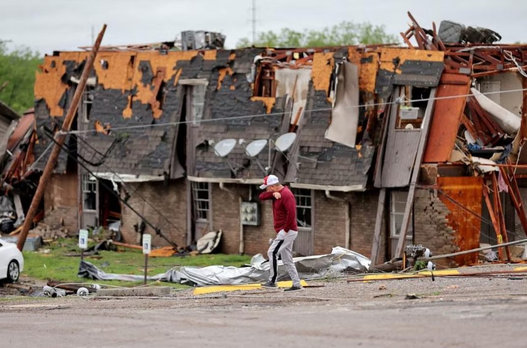 Một người đàn ông đi ngang qua tòa nhà bị hư hại sau khi nó bị lốc xoáy tấn công vào đêm hôm trước ở Sulphur, Oklahoma - Ảnh: Reuters