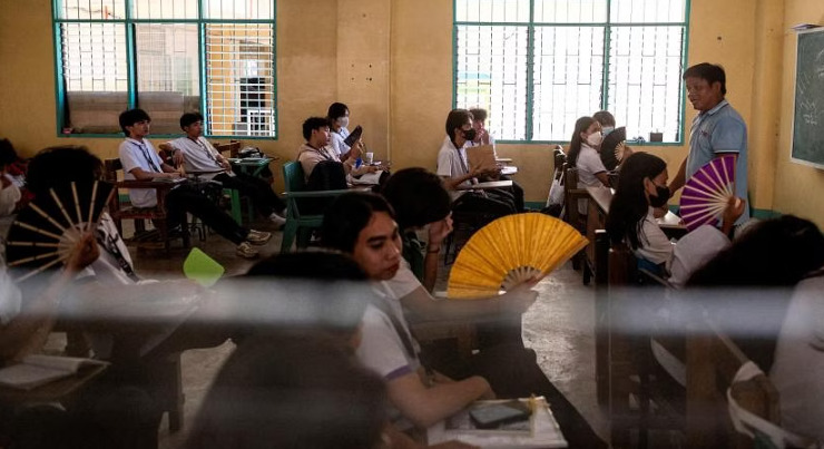 Học sinh lớp 12 sử dụng quạt cầm tay khi tham gia một lớp học tại Trường Trung học Commonwealth, ở thành phố Quezon, Metro Manila, vào ngày 18/4. ẢNH: REUTERS