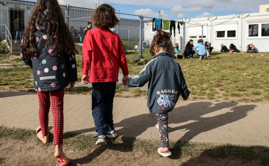Trẻ em đi bộ gần cơ sở giam giữ người di cư trái phép vào ngày 06 tháng 10 năm 2021 tại Eisenhuttenstadt, Đức. Hình ảnh Maja Hitij/Getty