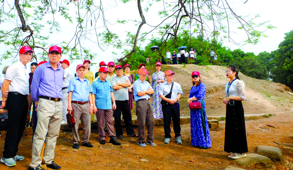 Trên đồi A1, thuyết minh viên (bìa phải) của Ban quản lý di tích tỉnh Điện Biên  giới thiệu với du khách từ lô cốt cây đa cụt đến hố bộc phá 960kg