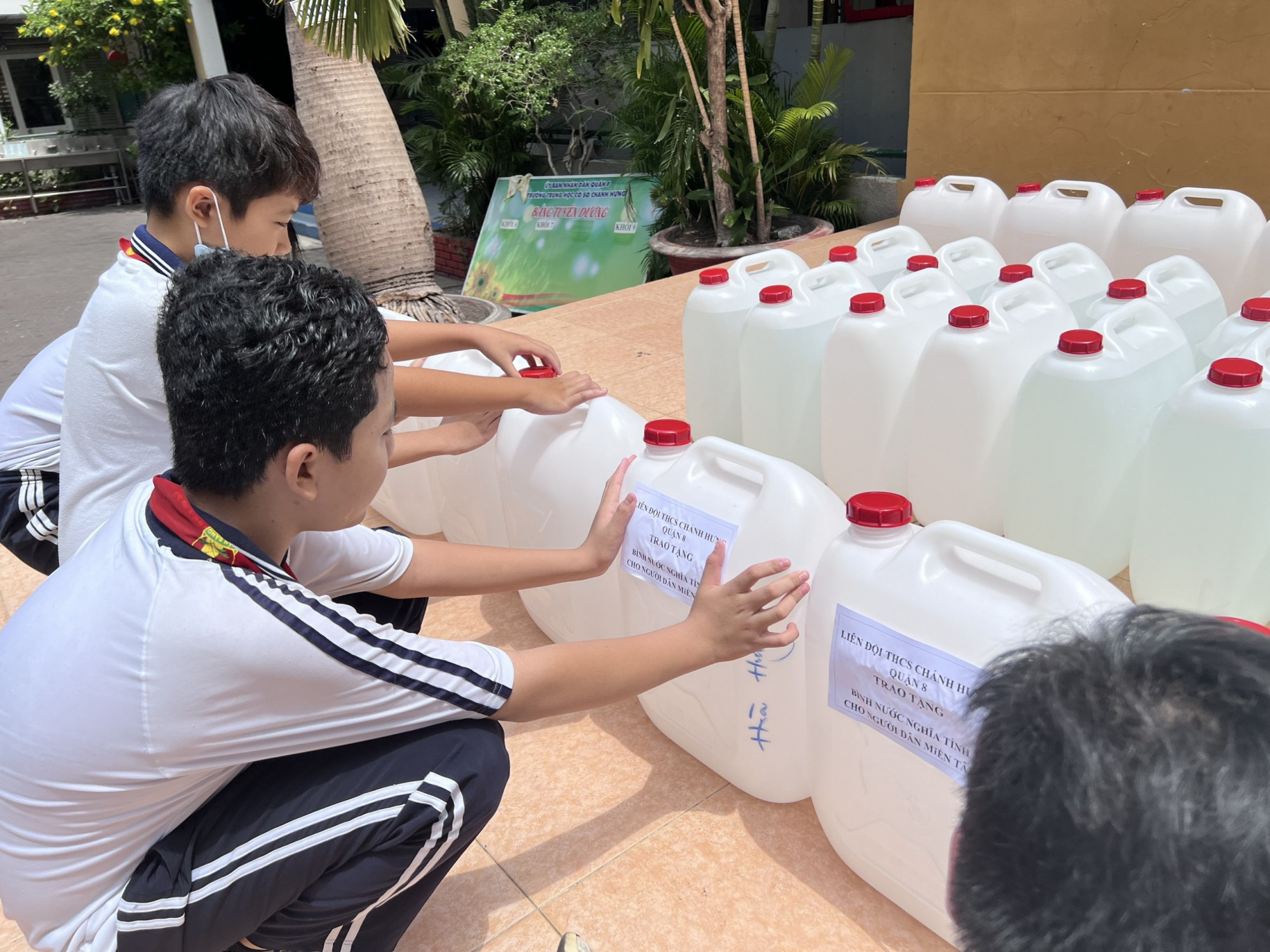 Học sinh Trường THCS Chánh Hưng (quận 8) bơm nước sạch vào can để gửi tặng bà con miền tây
