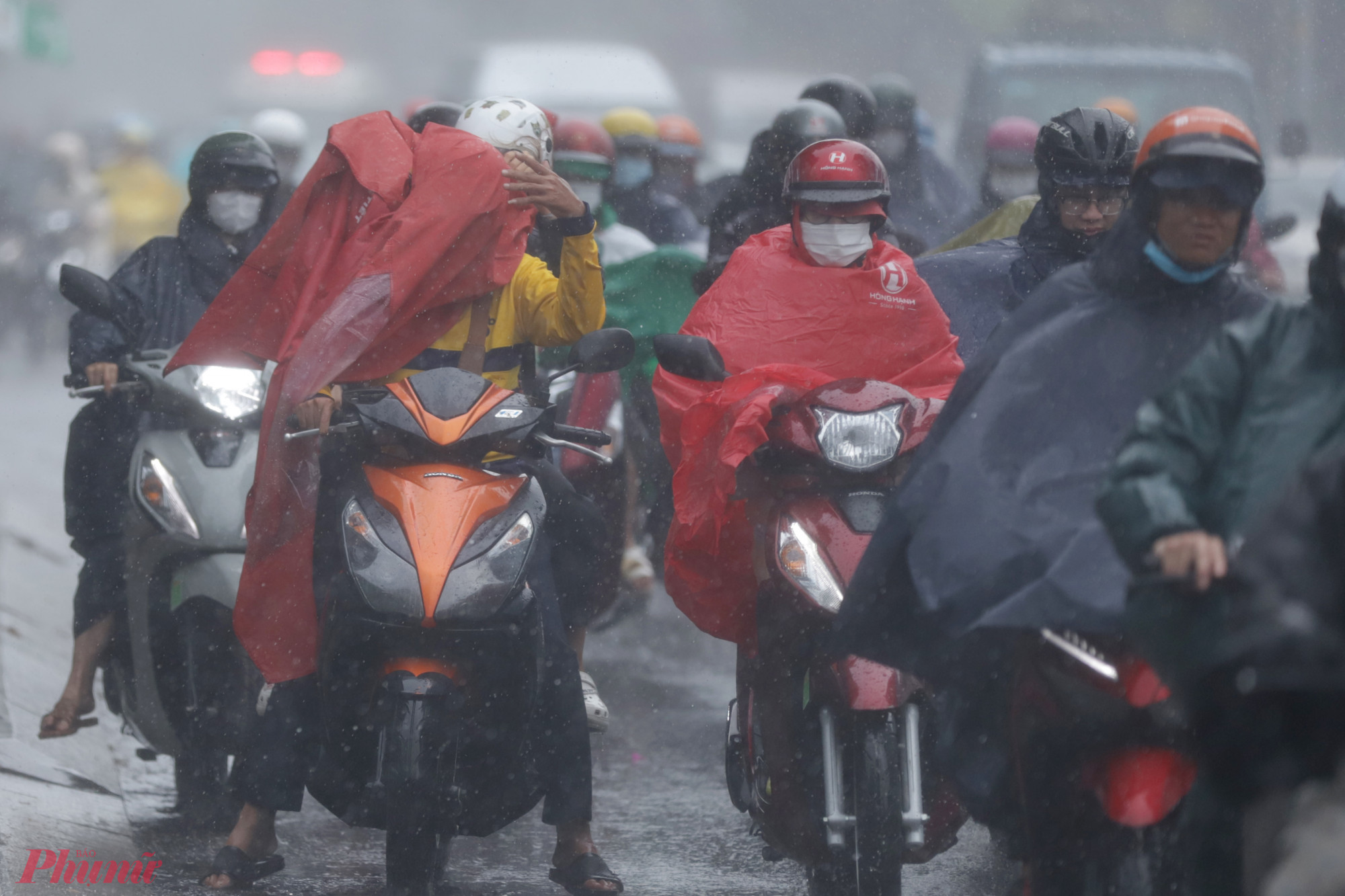 Mưa kèm theo gió giật mạnh làm áo mưa bay che kín mặt của nhiều người đi đường khá nguy hiểm.