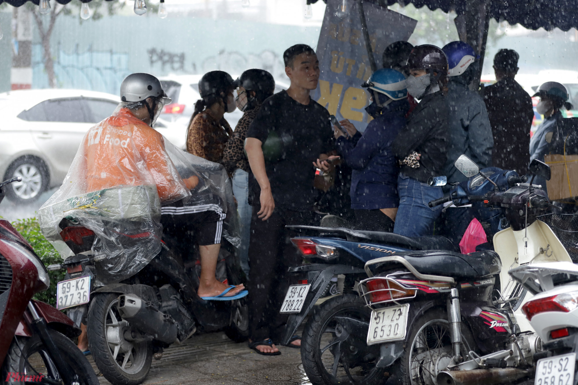 Mưa lớn kèm gió mạnh, nhiều người đi đường phải dừng lại trú tại các vỉa hè.