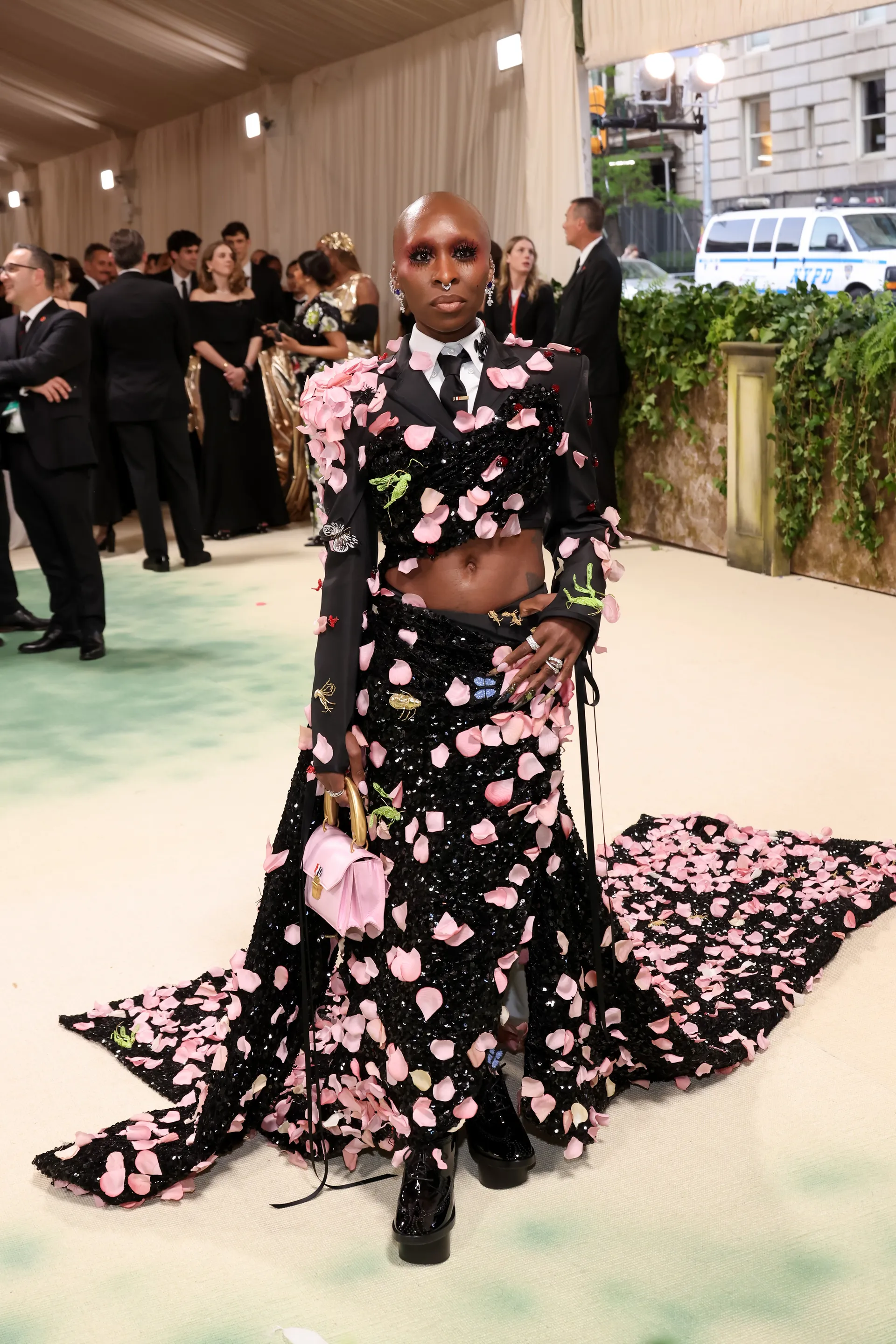 Cynthia Erivo bước đi trên thảm đỏ trong bộ đồ Thom Browne. Diện mạo đặc biệt của cô được bao phủ bởi 2.000 cánh hoa hồng lụa moiré với những hạt cườm được khâu tỉ mỉ trên khắp áo sơ mi.