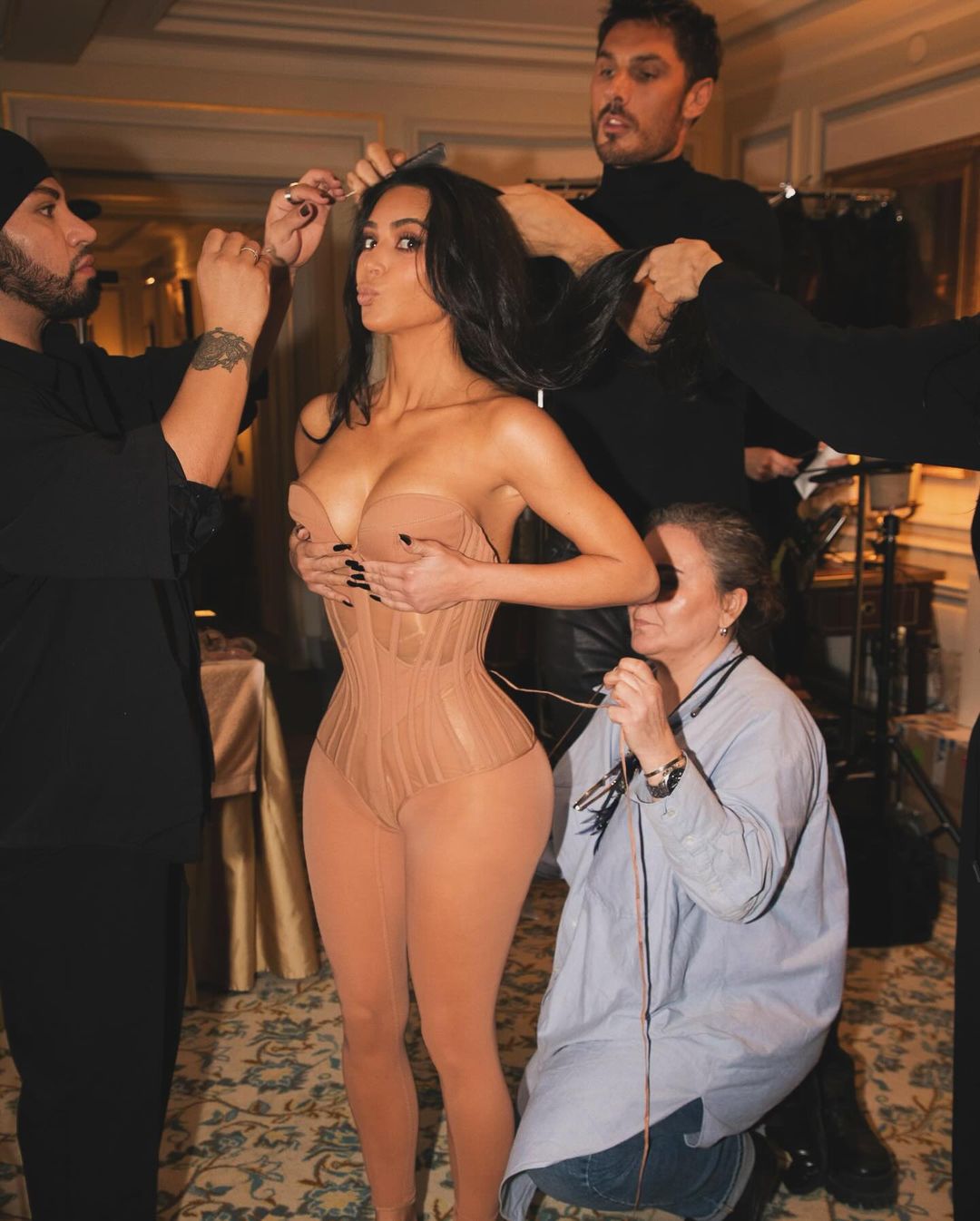 Kim Kardashian không ngần ngại chia sẻ ảnh hậu trường khi ê-kíp đang hỗ trợ cô mặc áo corset bó sát để có được vòng eo nhỏ xíu.