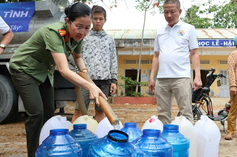 Trung tá Hoàng Thị Lan Phương – Trưởng ban Trị sự Báo Công an TPHCM – bơm nước từ xe bôn vào bình cho bà con chở về dùng.