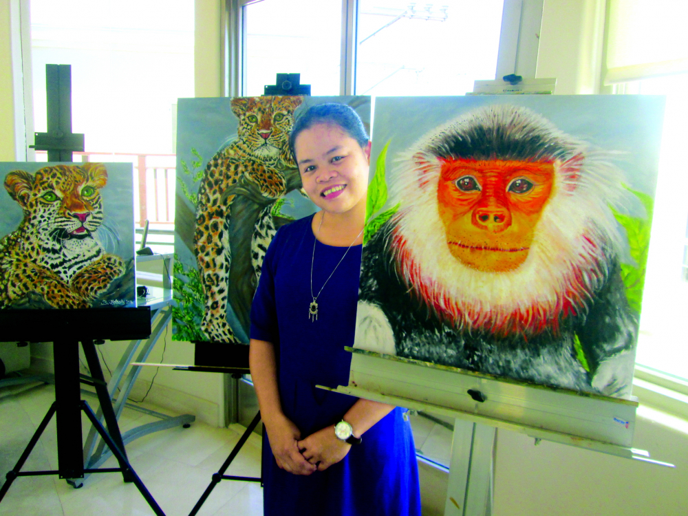Nhà bảo tồn Lê Thị Trang bên bức vẽ voọc chà vá chân nâu Sơn Trà của họa sĩ Beth Molasky