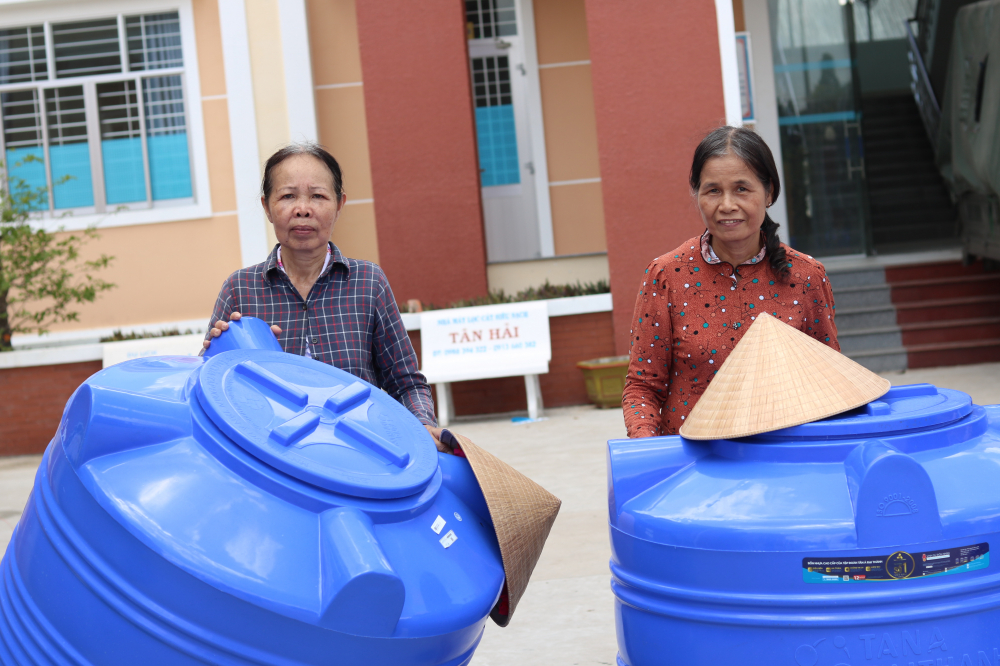 Bà Nguyễn Thị Hạnh (bìa phải, 67 tuổi, ở ấp Thạnh Đông, xã Hương Mỹ) kể,  do kinh tế eo hẹp bà phải “nhín” bằng cách mua nước bình về pha loãng nước máy cho giảm độ mặn để nấu ăn, dù biết như vậy không tốt cho sức khoẻ. Hiện, bà sống cùng mẹ già đã 98 tuổi, 2 mẹ con dựa vào thù lao bà gia công sản phẩm đan lát. 