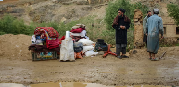 Người dân Afghanistan đứng bên cạnh đồ đạc của mình gần một ngôi nhà bị hư hại vào ngày 18/5 sau lũ quét ở Firozkoh, tỉnh Ghor, Afghanistan. Ảnh: AFP/Getty Images