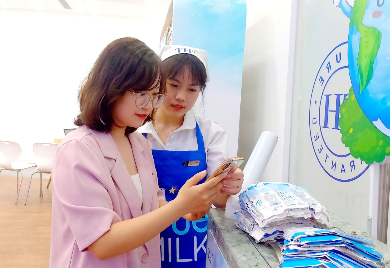 Chị Hiếu Ngân được nhân viên hướng dẫn quét mã quay thưởng khi đến TH true mart tham gia chương trình “Thu gom vỏ hộp, lan tỏa sống xanh 2024” - Ảnh: TH