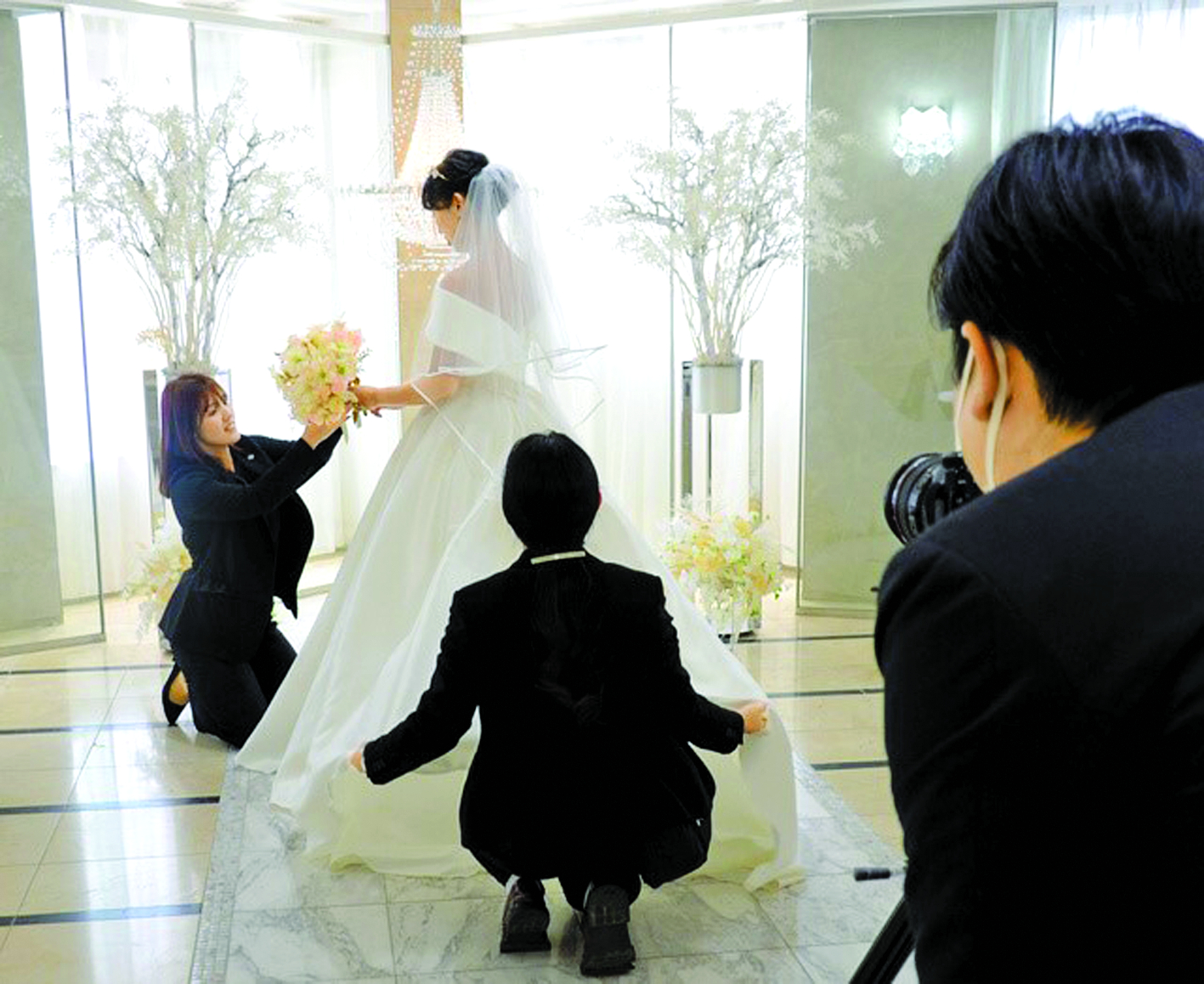 Nhân viên tại cửa hàng Petit Wedding chỉnh sửa váy áo cho vị khách nữ chụp ảnh cưới một mình - Nguồn ảnh: Asahi Shimbun