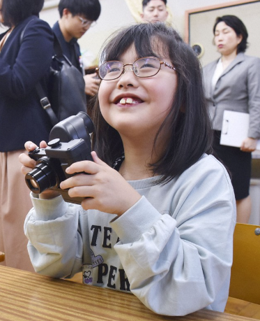 Một học sinh tại Trường Người mù Hachioji Thủ đô Tokyo cầm một chiếc máy ảnh được thiết kế dành cho người khiếm thị vào ngày 24 tháng 4 năm 2024, tại Hachioji, Tokyo. (Kyodo)