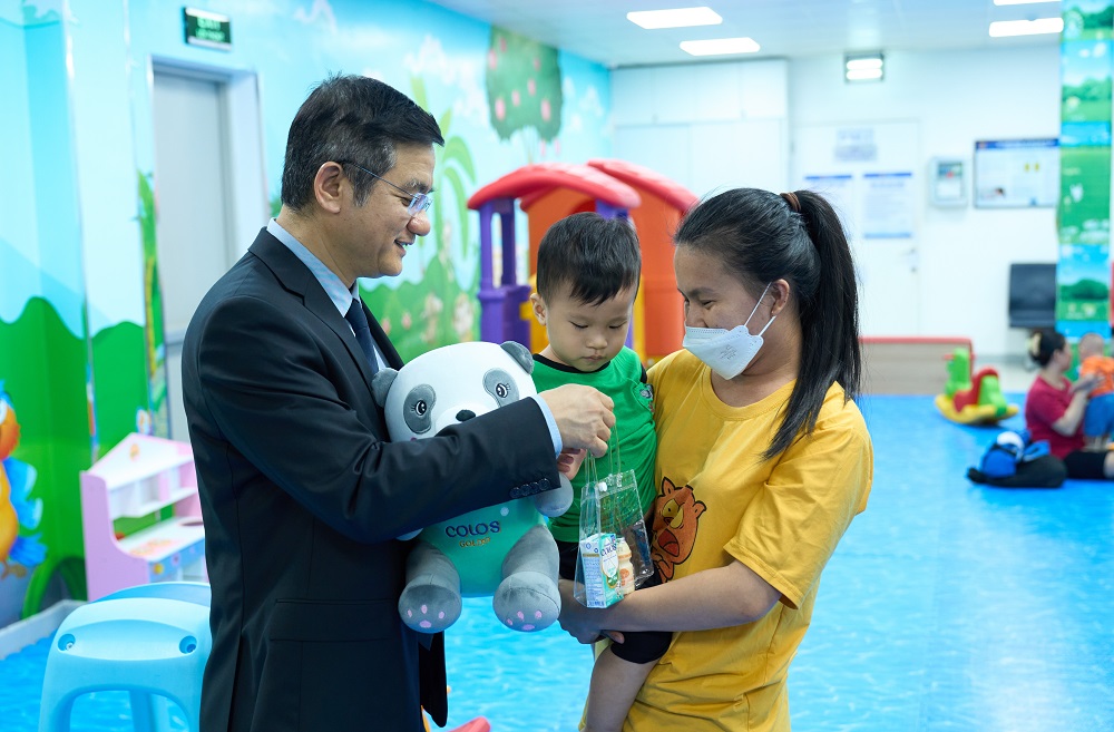 Ông Nguyễn Quang Trí - Giám đốc điều hành Vinamilk - tặng quà cho các gia đình, các bé đến tiêm ngừa tại Trung tâm VNVC trong ngày kí kết hợp tác - Ảnh: Vi Nam