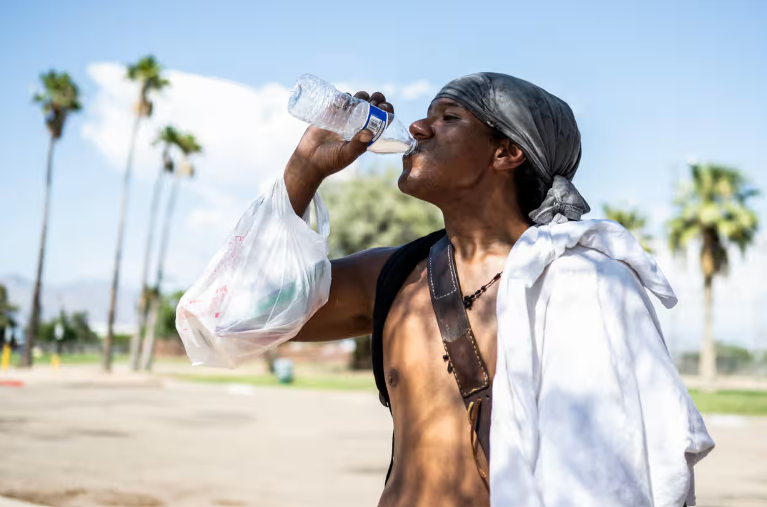 Một người đàn ông uống một chai nước trong đợt nắng nóng ở Tucson, Arizona  - Ảnh: AFP