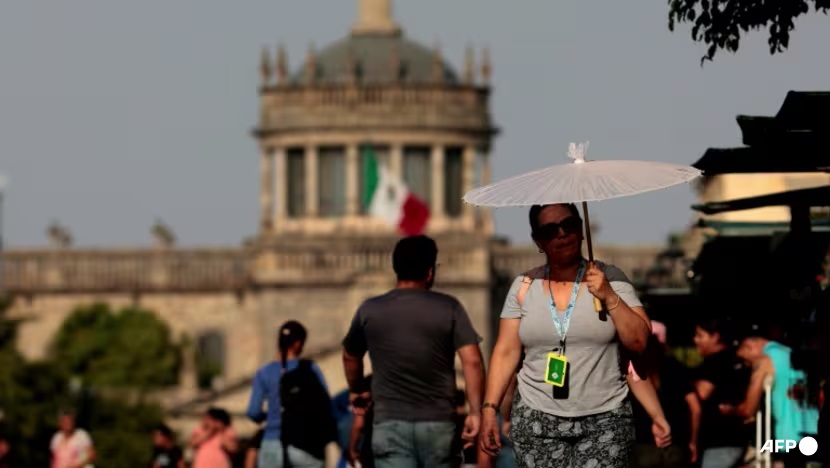 Người dân dùng dù che nắng trong đợt nắng nóng tại bang Jalisco, Mexico, vào tháng 5/2024 - Ảnh: AFP/ULISES RUIZ