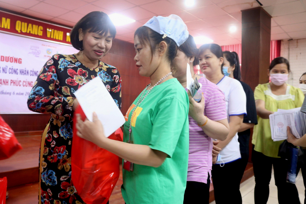 Ban tổ chức tặng quà cho 200 nữ công nhân, mỗi phần gồm nước giặt, giấy vệ sinh, các loại gia vị... Trong ảnh, bà Trần Thị Phương Hoa (bìa trái) – Phó chủ tịch Hội LHPN TPHCM – trao quà cho các chị. 