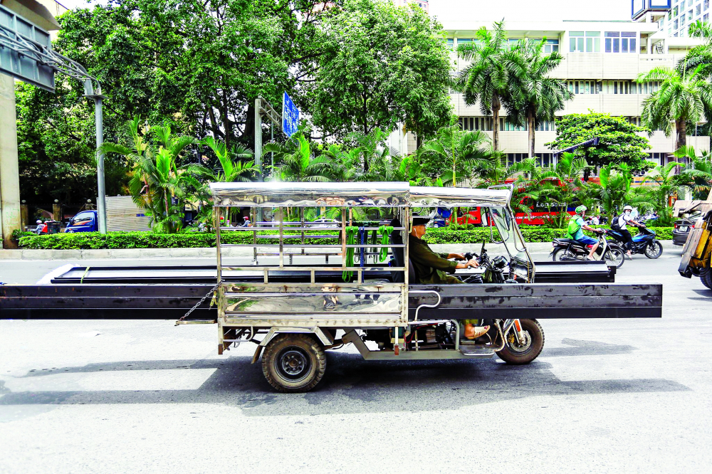 Một chiếc xe ba gác tự chế chở theo những khối sắt to và dài trên đường Quang Trung, quận Hà Đông, TP Hà Nội gây bất an cho người đi đường - ẢNH: NGỌC LINH