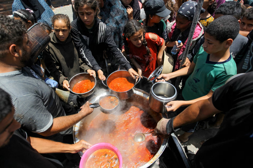 Người dân Palestine tụ tập để nhận thức ăn ở Khan Younis, phía nam Dải Gaza, ngày 19/6 - Ảnh: REUTERS/Hatem Khaled