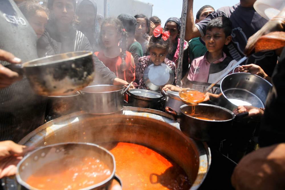 Người dân Palestine tập trung tại điểm nhận thức ăn do một bếp từ thiện nấu, trong bối cảnh thiếu hàng viện trợ ở Khan Younis, phía nam Dải Gaza - Ảnh: REUTERS/Hatem Khaled