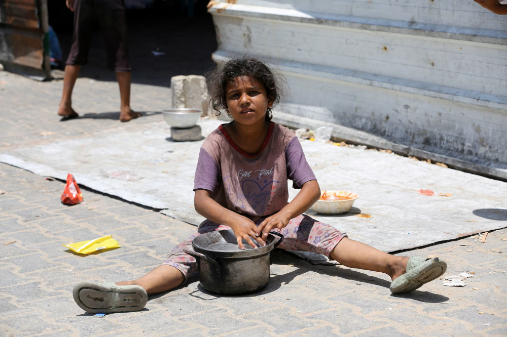 Một bé gái ngồi đợi thức ăn từ bếp từ thiện ở Khan Younis, phía nam Dải Gaza - Ảnh: REUTERS/Hatem Khaled