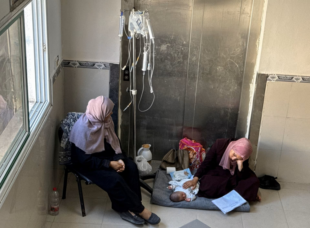 Một người phụ nữ Palestine nghỉ ngơi khi chăm sóc đứa con ốm yếu của mình tại bệnh viện Nasser ở Khan Younis - Ảnh: REUTERS/Mohammed Salem