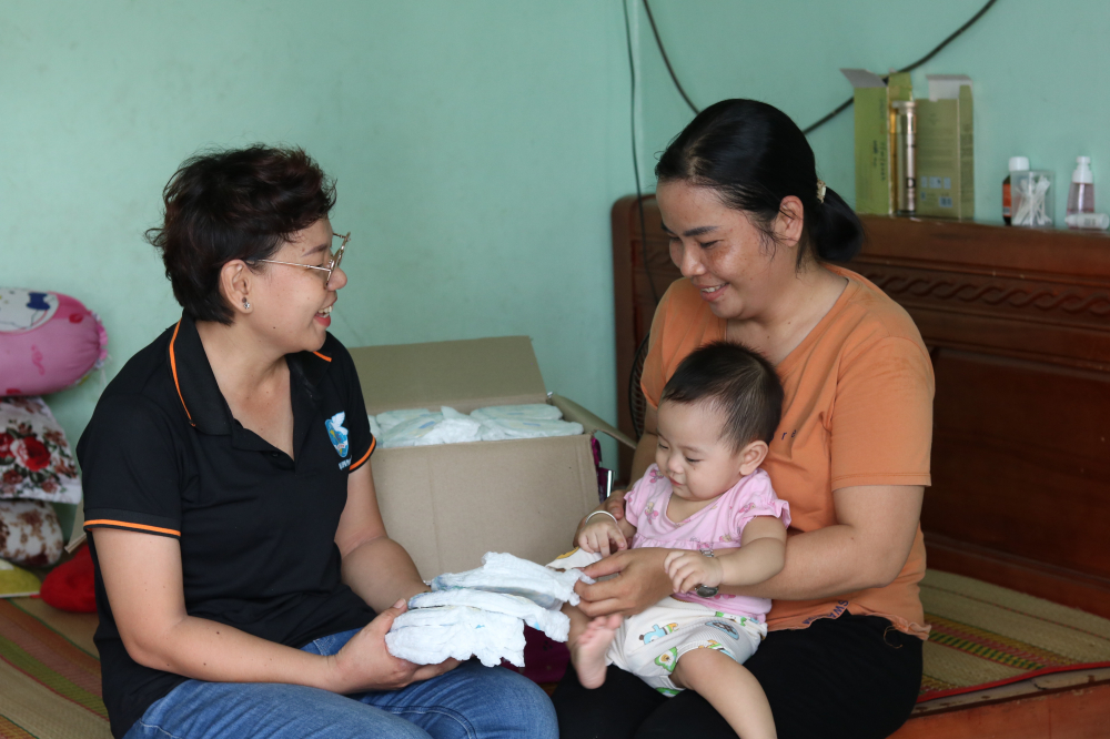 Trong khi mở chợ, chị Nguyễn Thị Phương Quyên (bìa trái) – Chủ tịch Hội LHPN phường Phước Long B – cũng đến tận các khu nhà trọ trao tã em bé cho những bà mẹ có con nhỏ. 