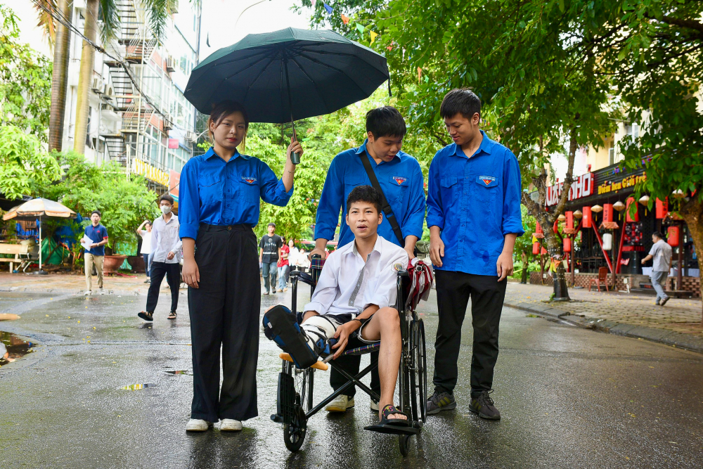 Một thí sinh bị gãy chân được hỗ trợ tại điểm thi trường THPT Cầu Giấy (Hà Nội)