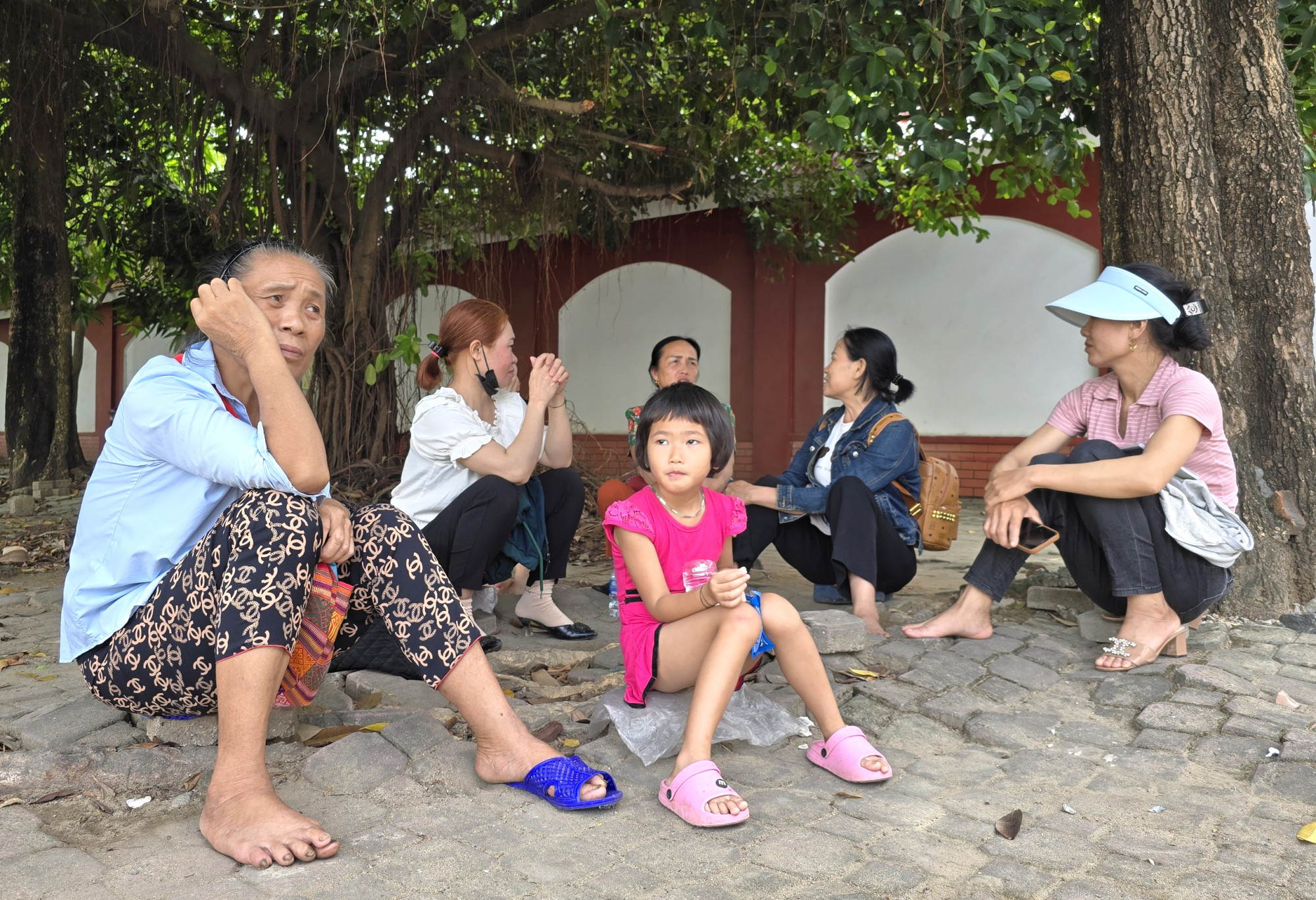 Bà Vi Thị Tơm ngồi túc trực trước cổng trường chờ cháu nội làm bài thi - Ảnh: Phan Ngọc