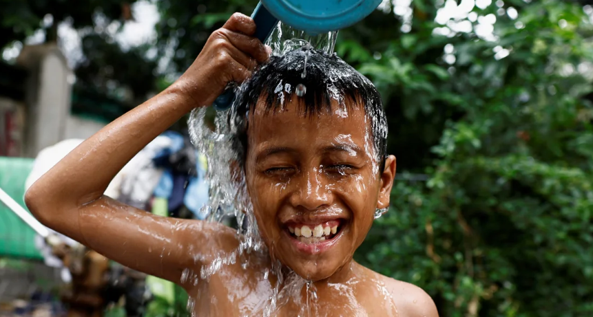 Một cậu bé dội nước lên người để giải nhiệt tại một giếng nước công cộng ở khu vực đông dân cư tại Jakarta, Indonesia, ngày 16 tháng 5 năm 2024